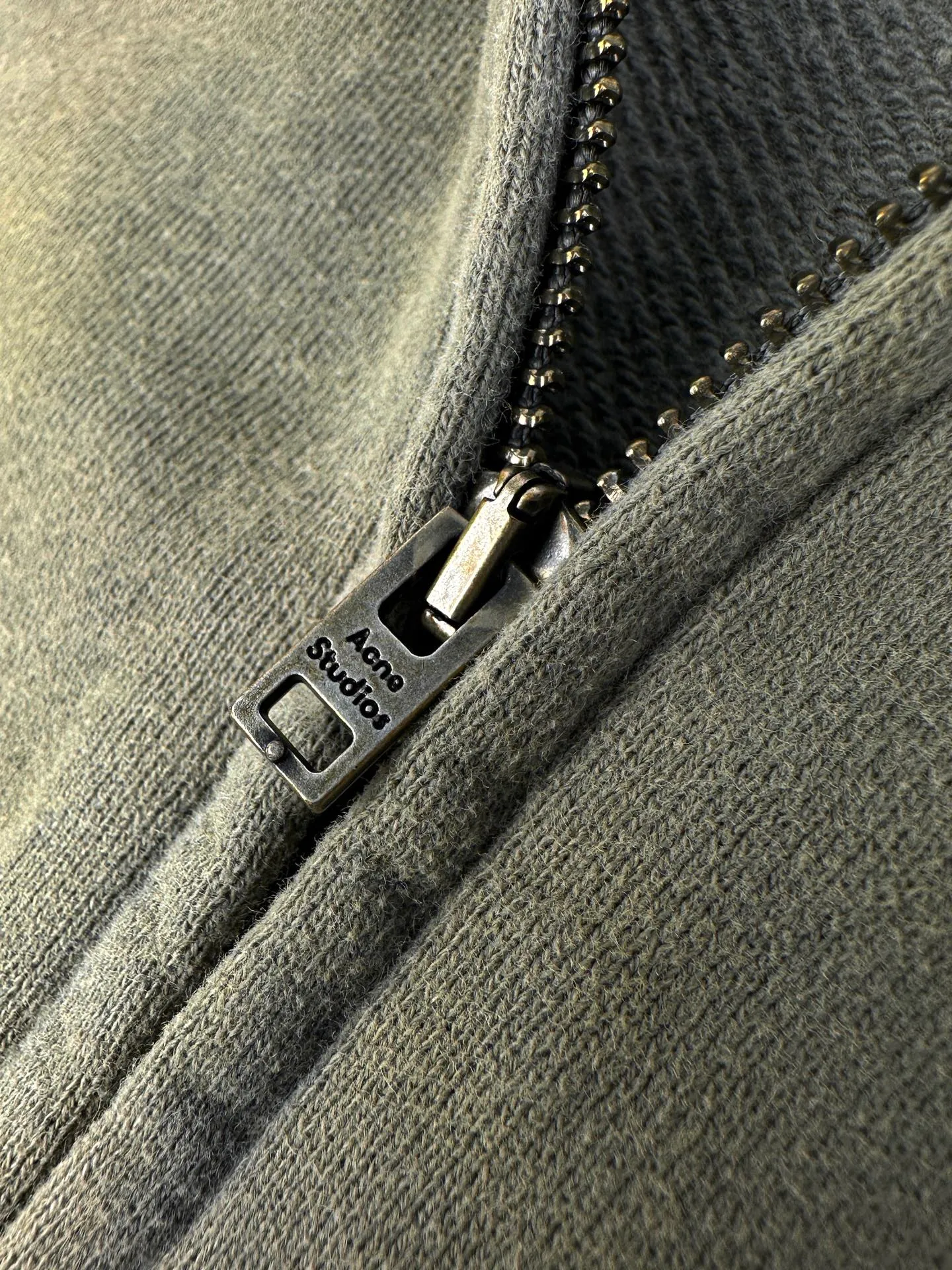 Acne Studi spray-painted distressed logo hooded jacket. Customized dusk-dyed acid-washed cloud-like fleece. Smooth drape. Soft and skin-friendly. Dressed in moss gray and green as a base. Water-washed and acid-washed soft fabric. Matte gray and green for a relaxed Retro street style. Raglan sleeves with full zipper and hooded silhouette. Acne Studios print on the left chest. Low-key and restrained without being ostentatious. Hand-made distressed repair texture in many places on the body. Retro traces simulated wear and repair, giving the garment a sense of narrative. Classic kangaroo pockets are practical and appropriate. Ribbed cuffs and hems lock the silhouette of the body. Integrate worn-out Retro aesthetics into daily life with the deconstructed ready-to-wear language. Interpret the relaxed high-end posture of the Scandinavian pioneers. Process 1: Adopt glue printing process. The chest printing has been revised three times with the film screen. Use glue liquid paint to print the pattern on the fabric. Bake the fabric to fix the printed pattern. Process 2: Use imported machine embroidery process. Use advanced computer control systems and precision mechanical components to achieve detailed patch work with high precision and smooth and delicate lines. Process 3: Gradient distressed spray process. By spraying dyes of different colors on the surface of the fabric, the clothes can show rich color changes under different lights and increase the visual layering. Process 4: Many parts of the body are worn by pure manual regular positioning and manual brush marks. Add texture and depth to the surface of the clothing to imitate the texture of natural wear. Process 5: The fabrics have been fermented and washed. Better hand feel, not easy to deform, not easy to shrink, not easy to fade, maintains long-term beauty. Accessories: Customized 1:1 Acne zipper. Customized 1:1 Acne trademark. Version: Loose version. Size: S M L XL. Style number: CC 7003.